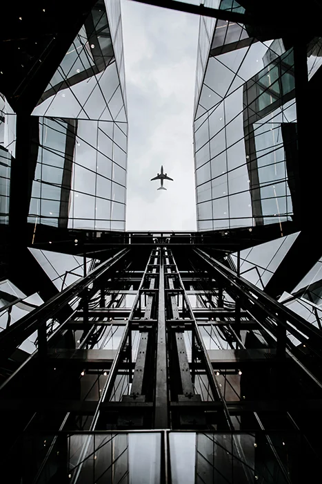 An iPhone shot of an aeroplane passing over a glass covered building