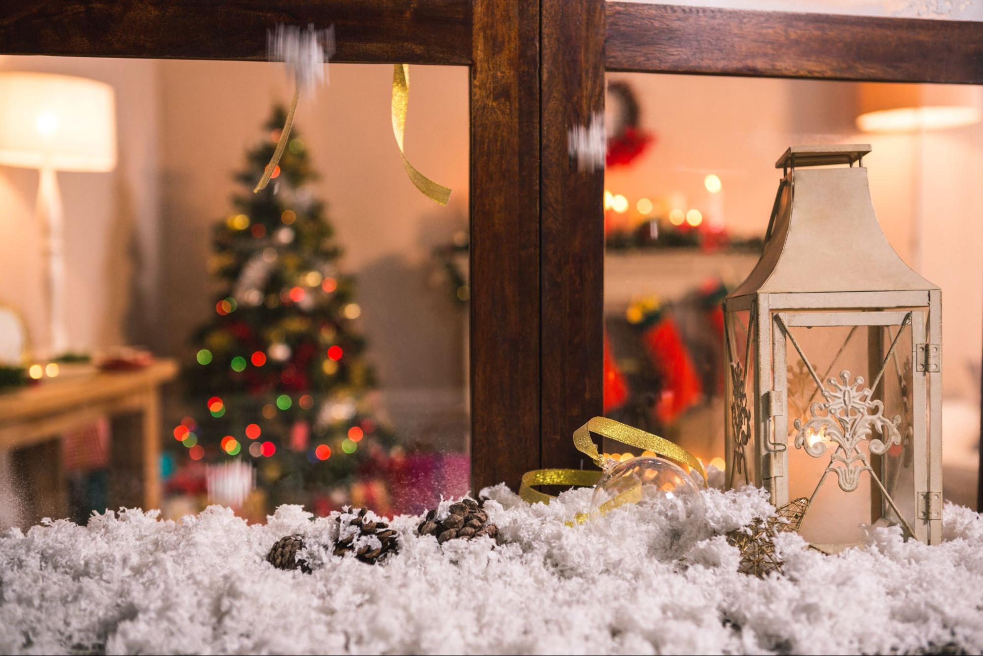 Festive Christmas tree and lantern in front of a window, creating a cozy holiday ambiance